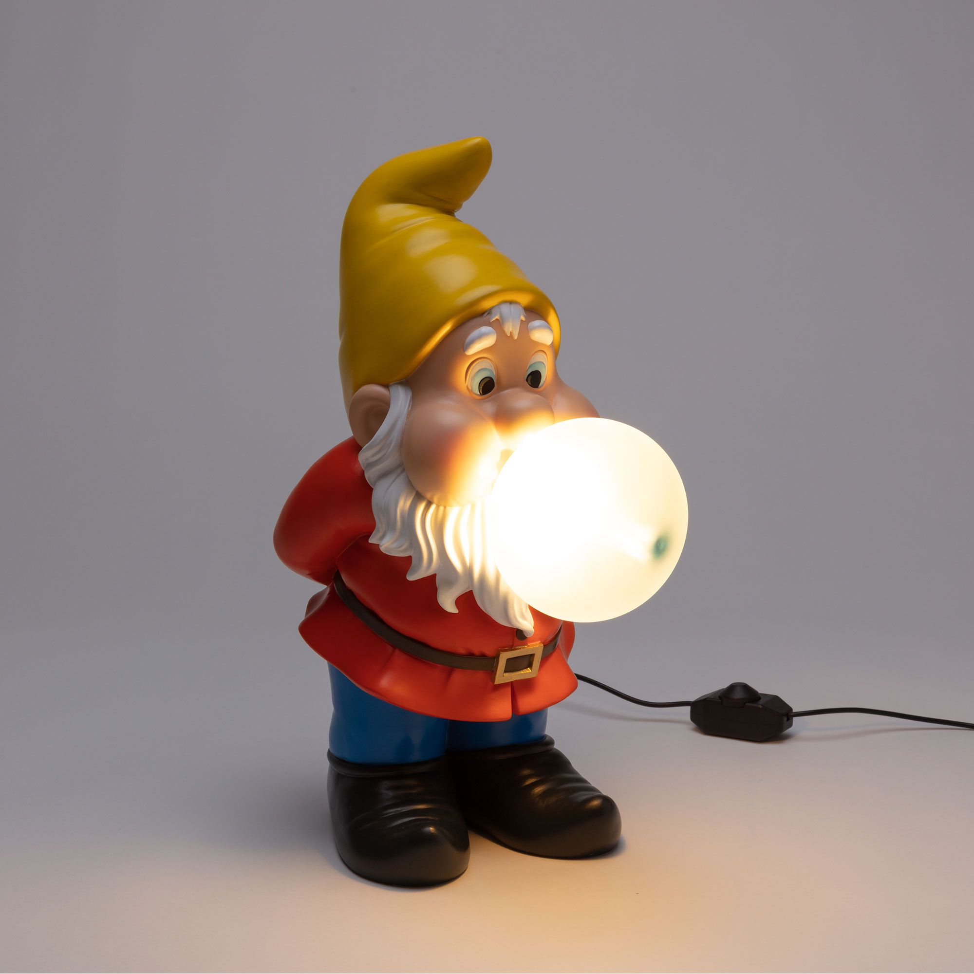 Seletti Gummy Snooping Lampe: Lustige Zwergen-Tischleuchte mit gelbem Hut und leuchtender Kugel im Mund.