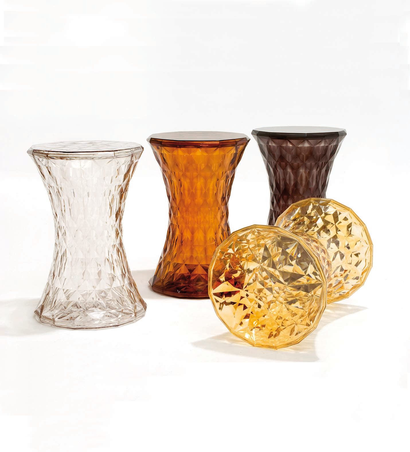 Mehrere Kartell Stone Hocker in transparent, rotbraun und braun mit geometrischem Design.