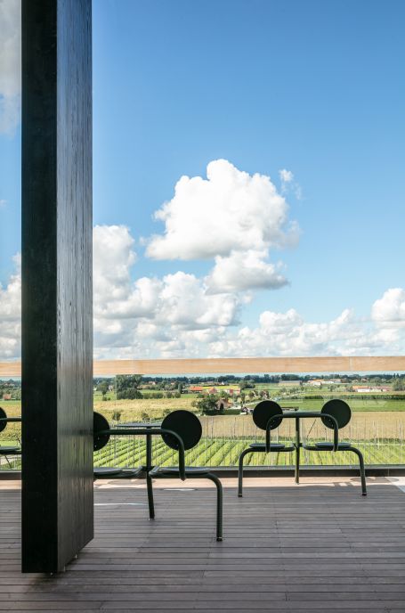 Extremis Bistroo Outdoor Stuhl-Tisch-Kombination auf Holzterrasse mit Blick auf grüne Landschaft und blauem Himmel.
