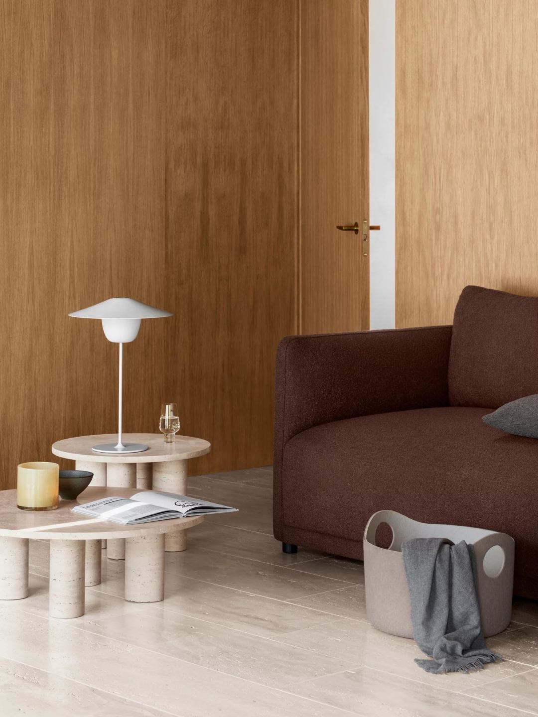 Blomus Volos Couchtisch aus Travertin, rund, mit Lampe, Buch und Dekoration im Wohnzimmer.