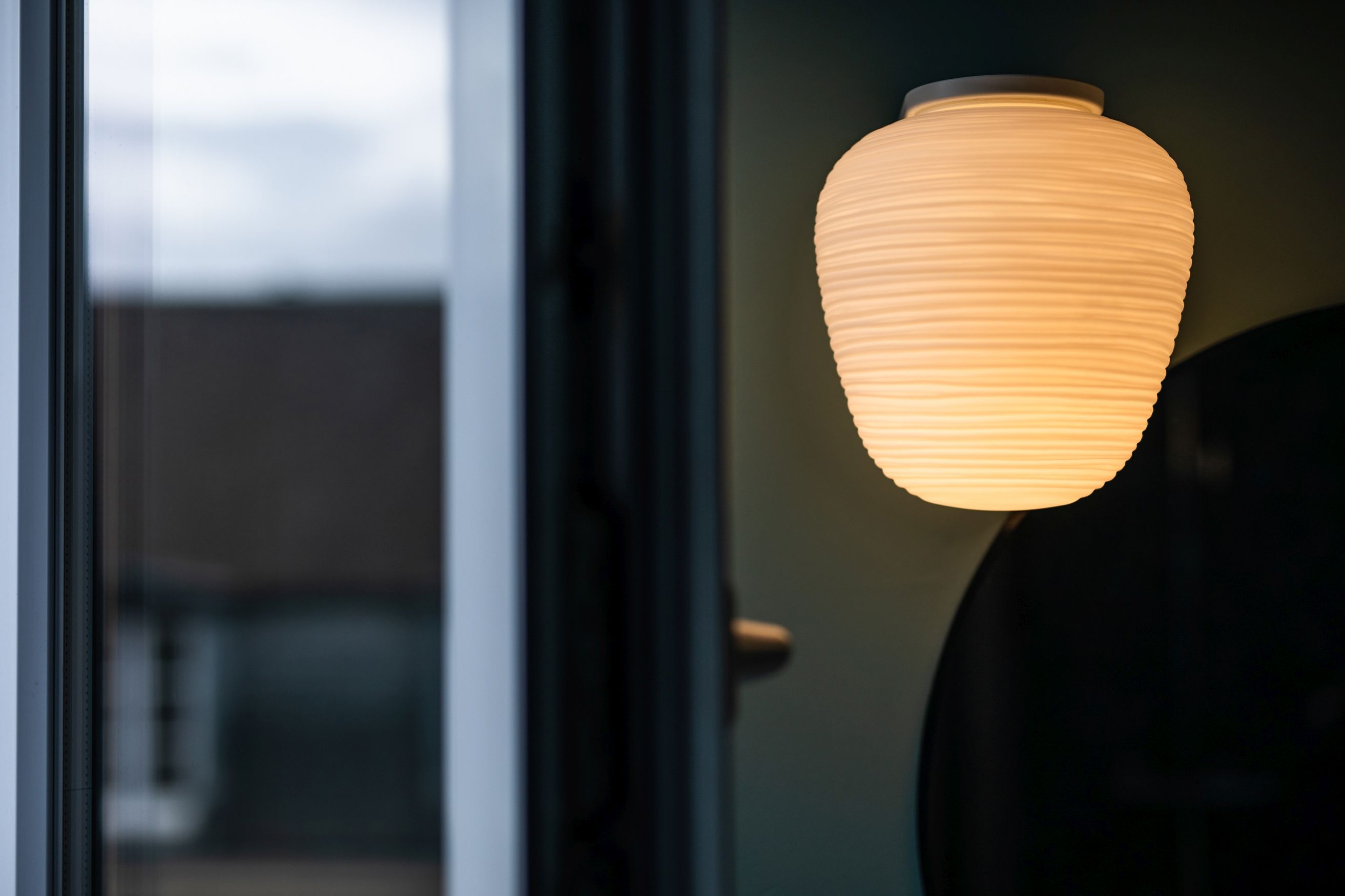 Nahaufnahme der Rituals Wandleuchte von Foscarini, die ein warmes, gedämpftes Licht in einem modernen Interieur ausstrahlt.