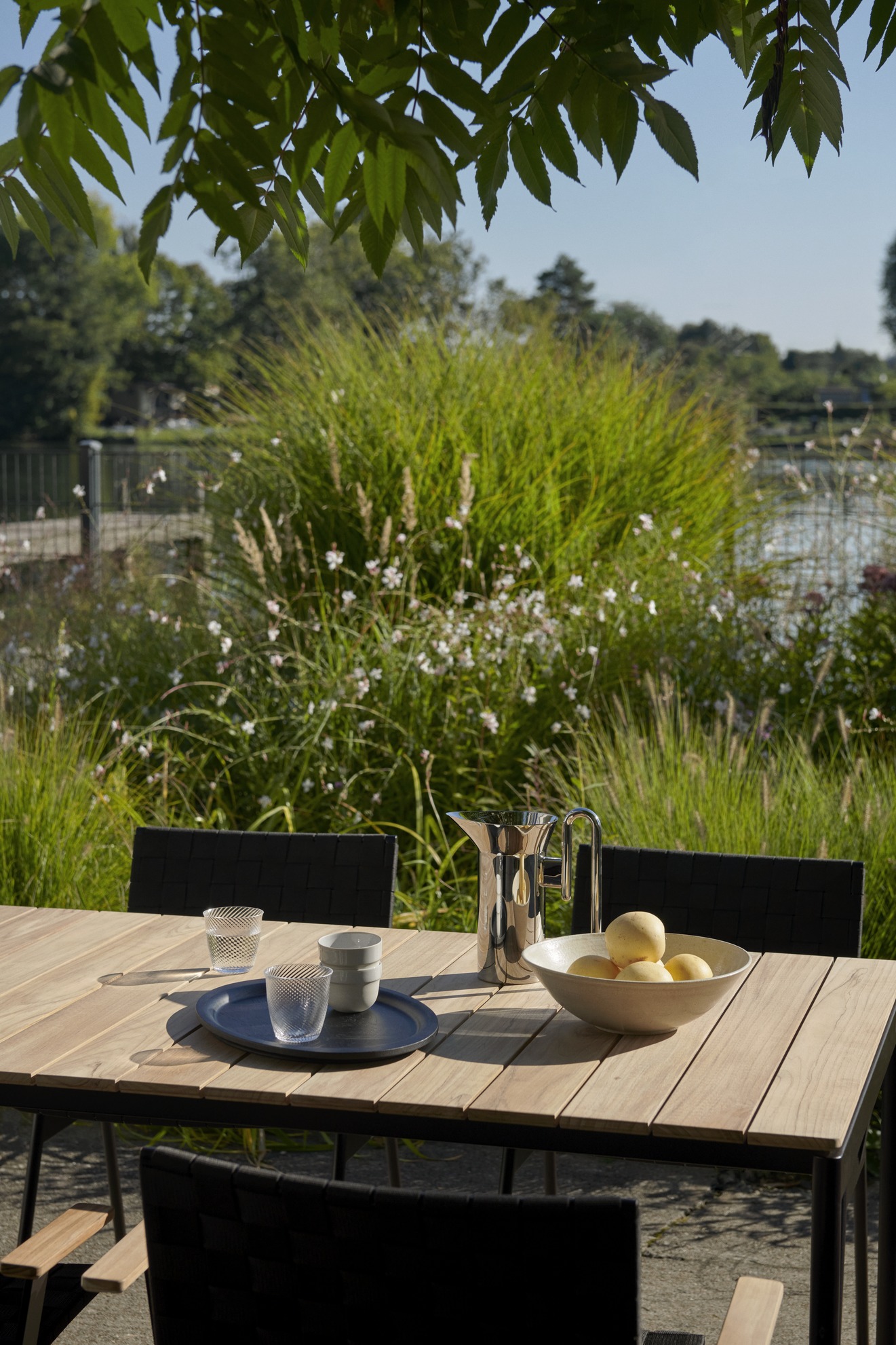 Ville AV25 Outdoor Tisch von AndTradition auf einer Terrasse mit Geschirr und Dekoration.