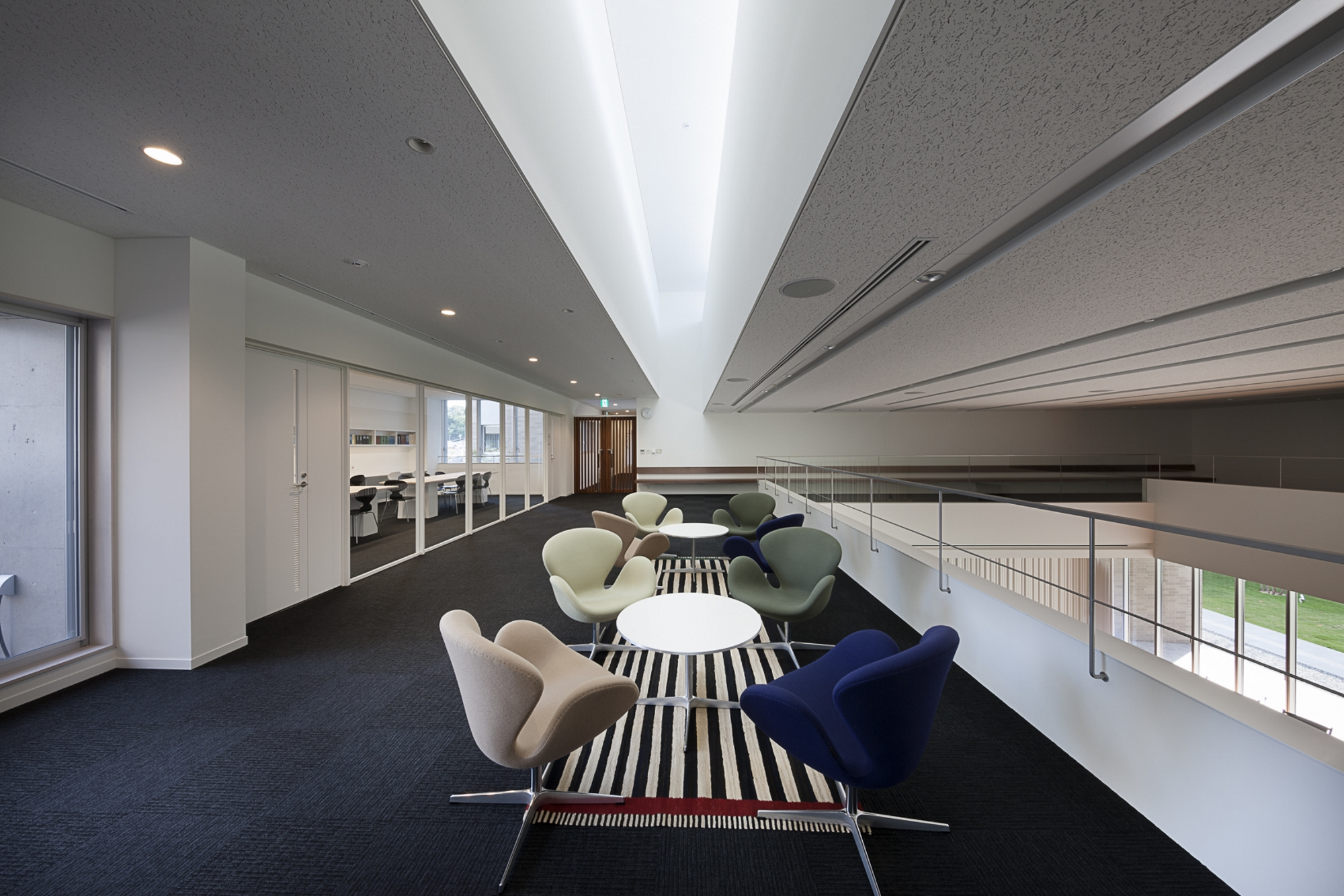 Mehrere Fritz Hansen Schwan Sessel in Beige, Blau und Grün um weiße Tische in modernem Büro.