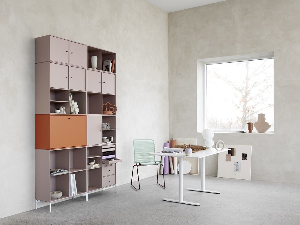 Heller Raum mit Montana HiLow 2 höhenverstellbarem Schreibtisch und großem Regalsystem in Pastellfarben.