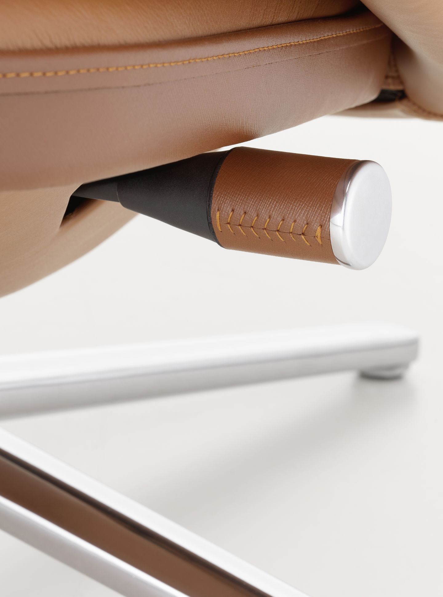 Detailaufnahme: Verstellhebel und Fußkreuz vom Vitra Grand Relax Sessel mit braunem Lederbezug.