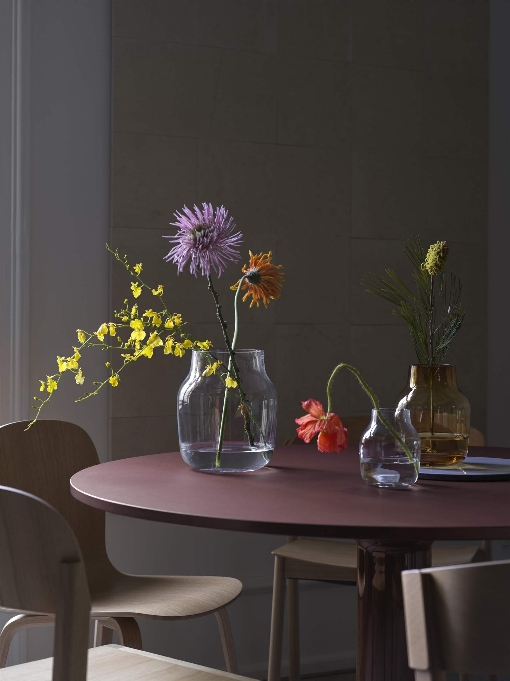 Nahaufnahme des Muuto MIDST Table Esstisches mit Blumenvasen, umgeben von Holzstühlen in einem stilvollen Esszimmer.