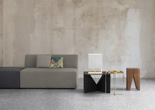 SF06 Kerman Modulsofa von e15, graues Stoffsofa mit Kissen und Beistelltischen vor beiger Wand.