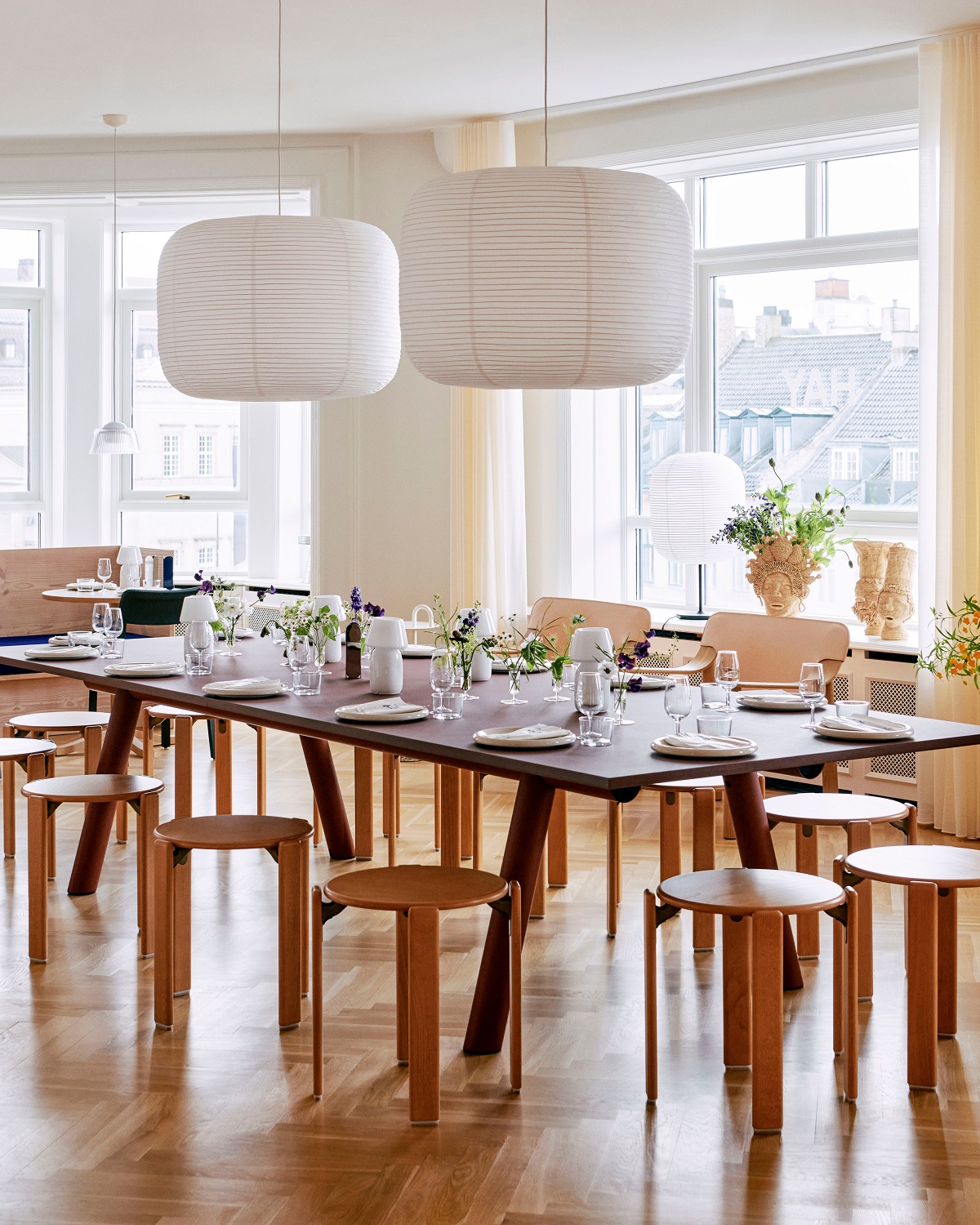 Helles Esszimmer mit großem Tisch und Hay Paper Shade-Donut Lampenschirmen in Weiß über dem Tisch.