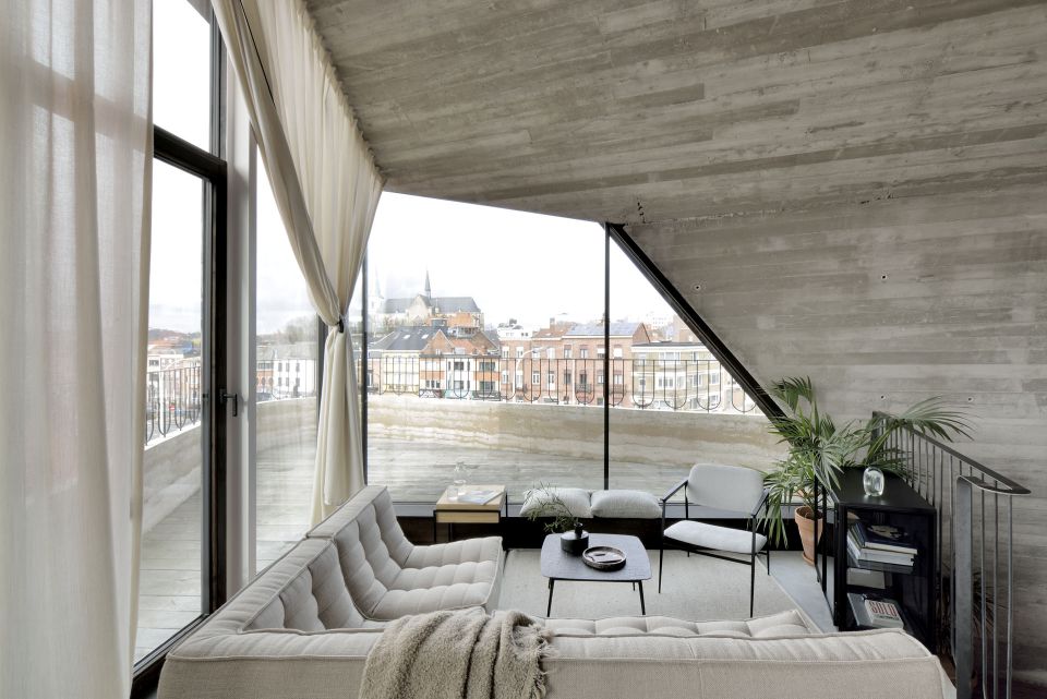 Helles Wohnzimmer mit Ethnicraft Sofa, N701 Ecksofa, Couchtisch und großem Fenster mit Stadtblick.