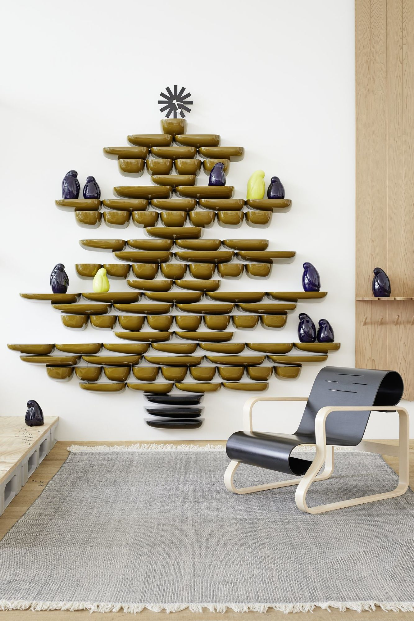 Raumansicht mit Vitra Corniches Wandboards in Olivgrün, die wie ein Weihnachtsbaum an der Wand hängen.