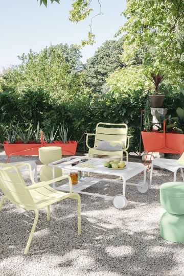 Gelber Luxembourg Lounge Sessel von Fermob im Garten mit passendem Outdoor Tisch und Dekoration.