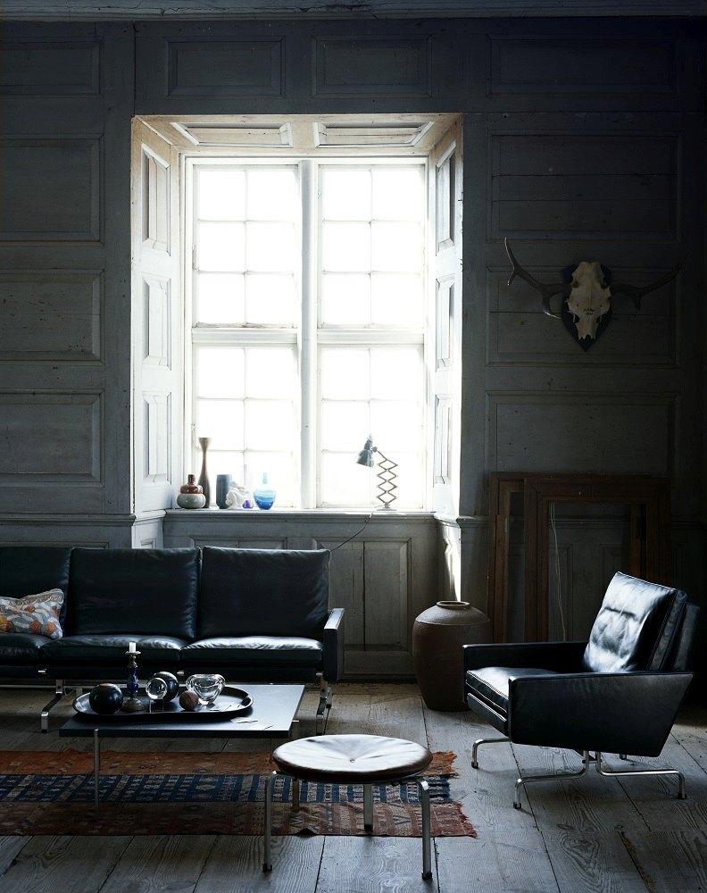 Wohnzimmer mit schwarzem Ledersofa, Sessel und PK 33 Hocker von Fritz Hansen.