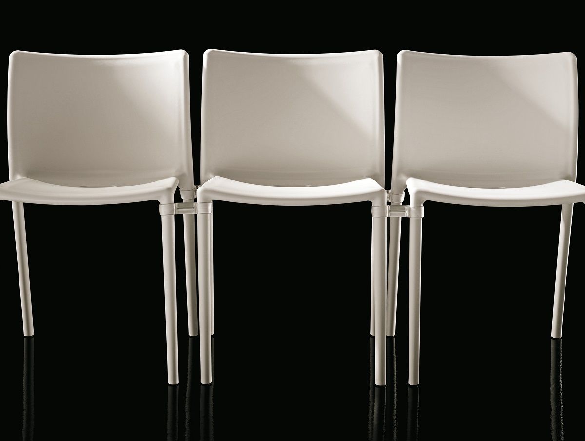 Drei weiße Air Chair Stühle von Magis für drinnen und draußen vor schwarzem Hintergrund.