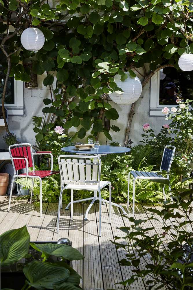Haefeli Stuhl Outdoor in Graublau (RAL 5008) auf einer Terrasse mit Tisch und Garten.