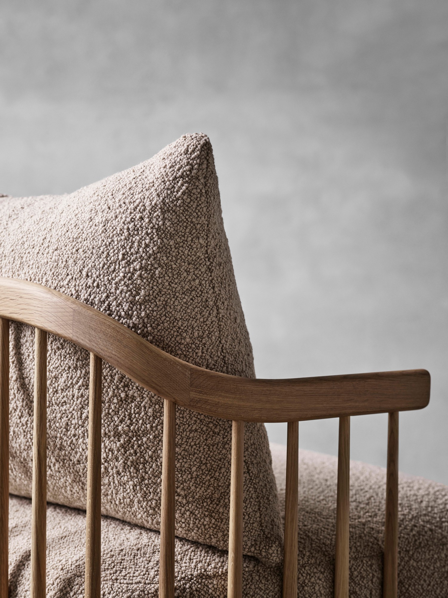 Detailaufnahme des Fly Lounge Sessels von AndTradition mit Bouclé-Polsterung und Holzgestell.