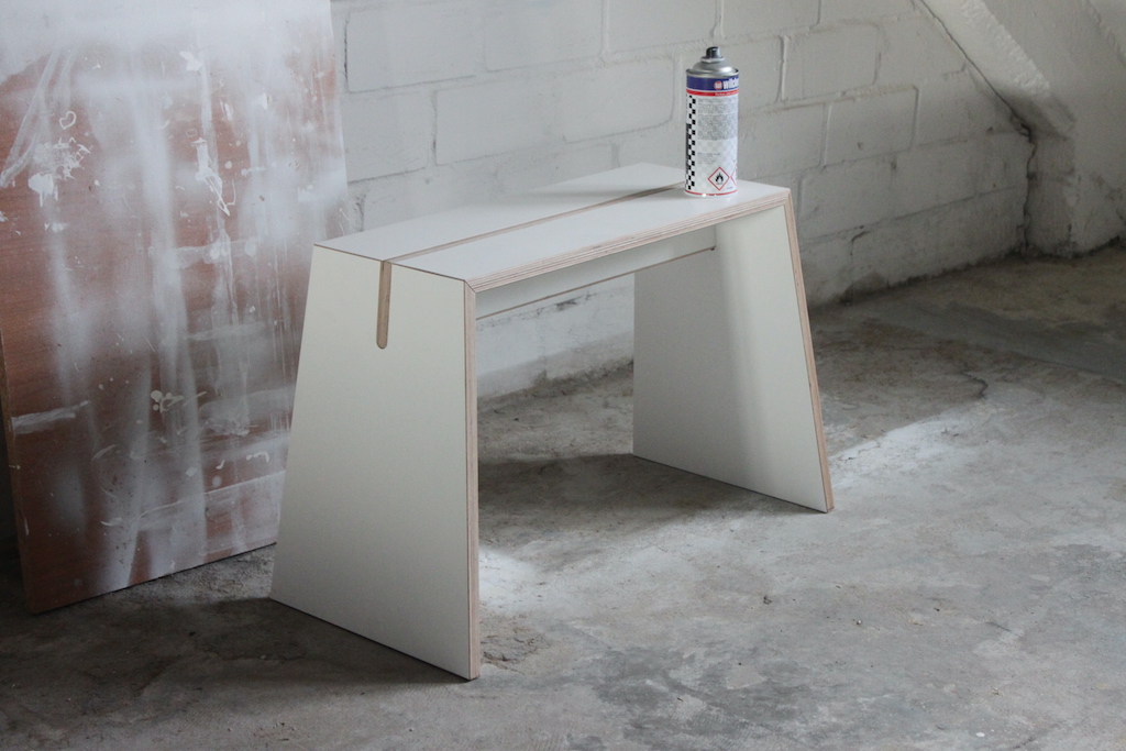 Tojo Stubenhocker: Moderner, weißer Hocker aus Holz mit minimalistischem Design und einer Sprühdose darauf.