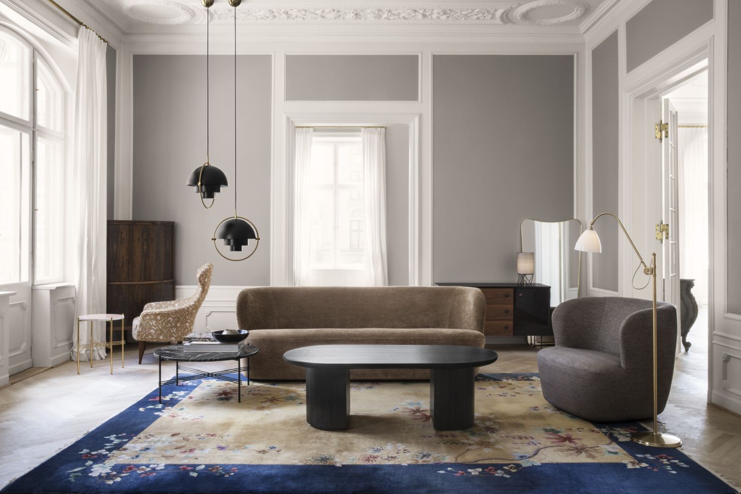 Elegantes Wohnzimmer mit Gubi 62 Sideboard, Sofa, Sessel, Teppich und Pendelleuchten in stilvollem Ambiente.
