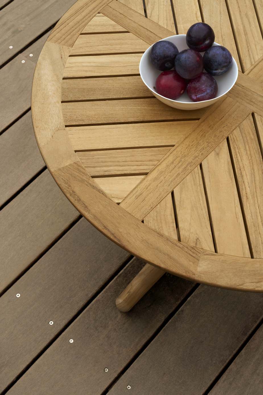 Detailaufnahme des Carl Hansen & Søn E023 Embrace Lounge Tisch Outdoor mit Pflaumen in einer Schale.