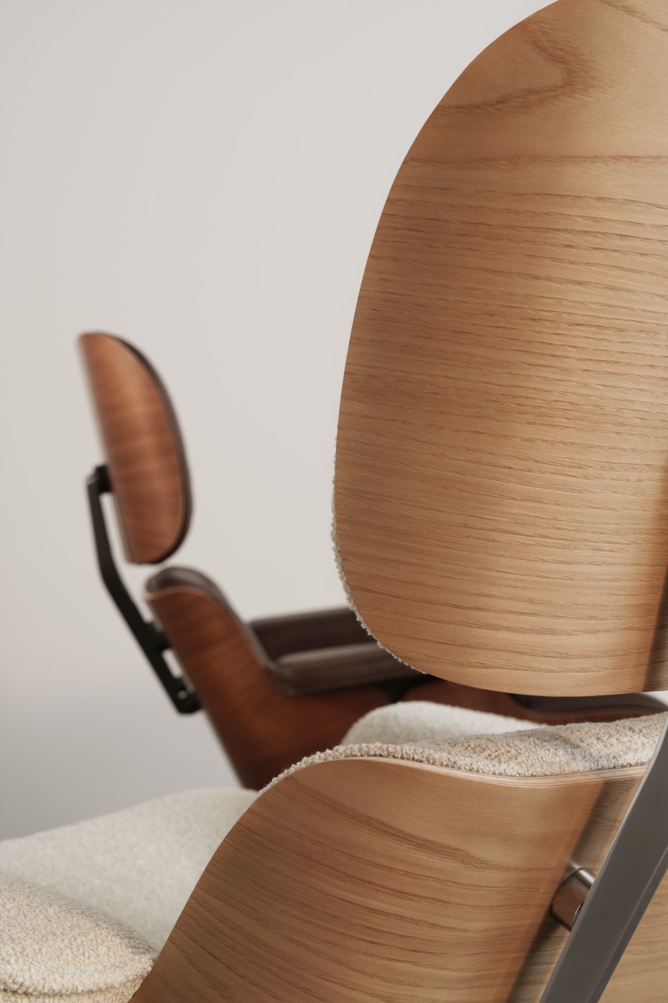 Detailaufnahme: Eames Lounge Chair Sessel mit hellem Bezug und Holzschale, Designklassiker für Wohnzimmer und Büro.