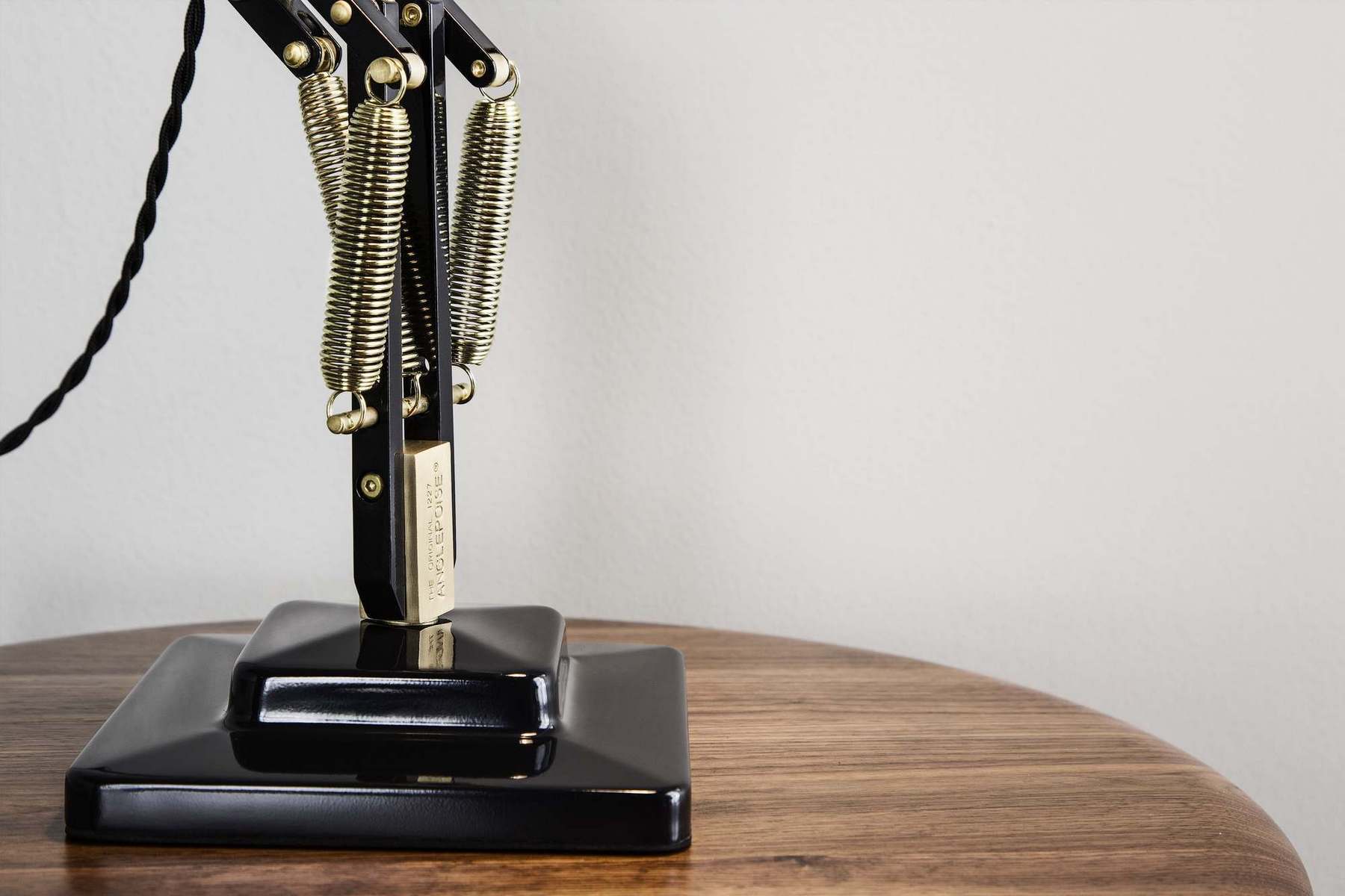Detailaufnahme der Original 1227 Anglepoise Tischleuchte in Messing und Schwarz auf einem Holztisch.