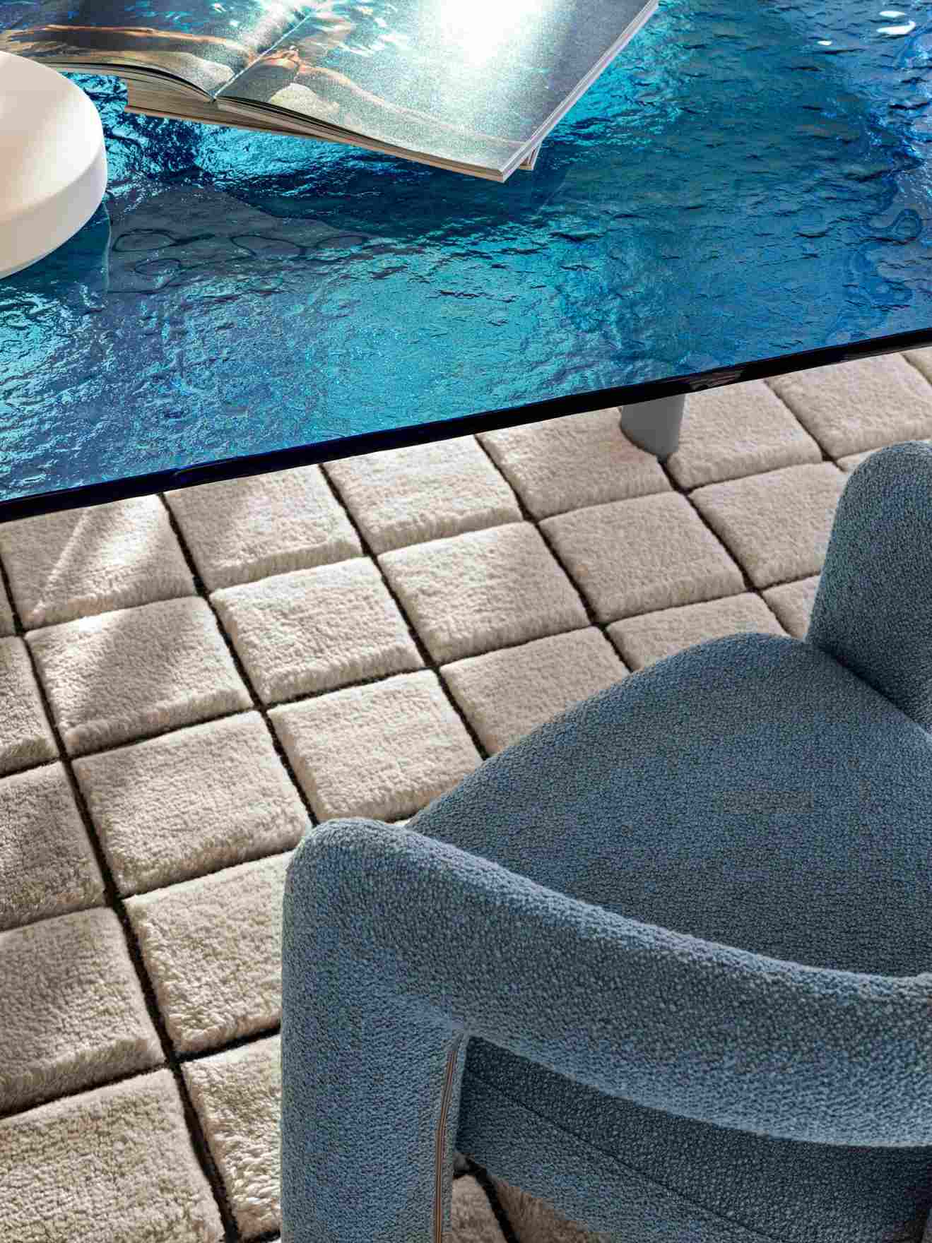 Nahaufnahme des blauen Cassina 562 Dudet Sessels auf einem quadratischen Teppich, kombiniert mit einem blauen Tisch.