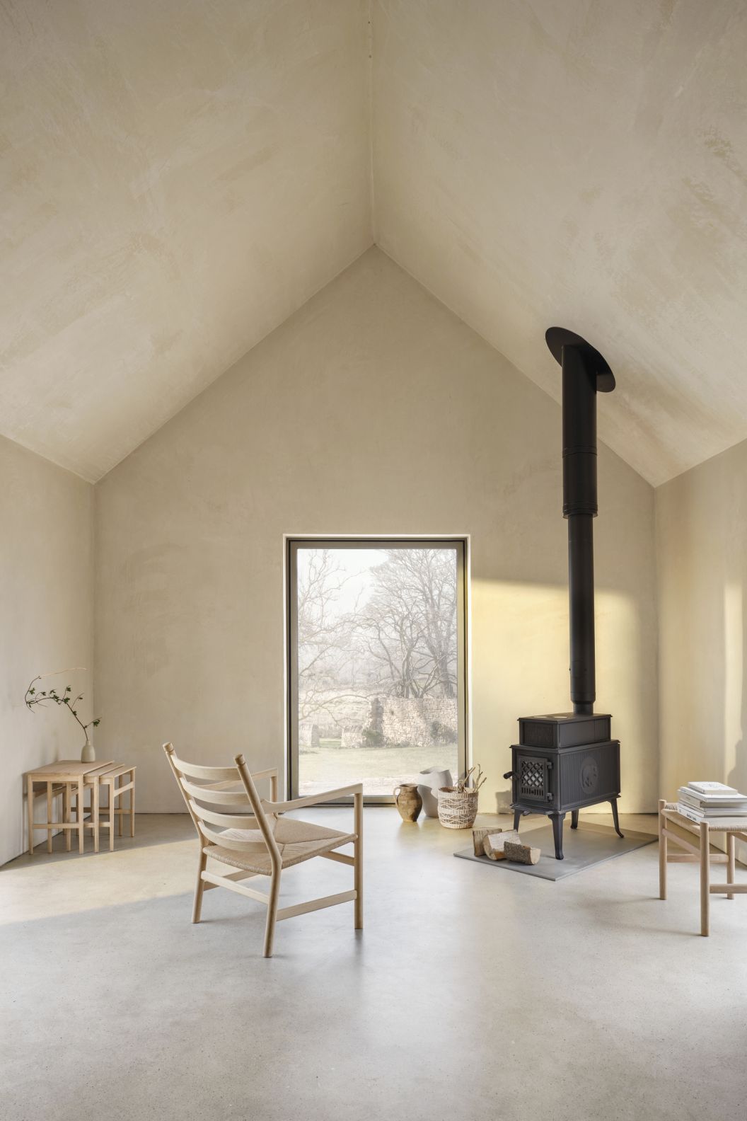 CH004 Nesting Tables Beistelltische von Carl Hansen & Søn im minimalistischen Wohnzimmer mit Kamin und Sessel.