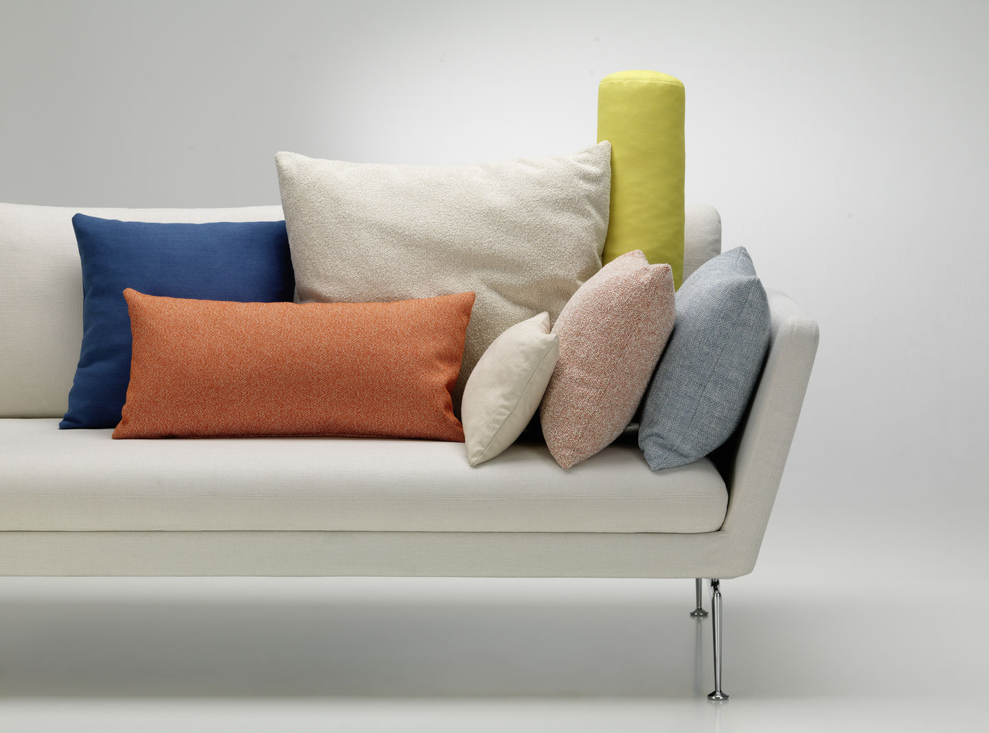 Vitra Kissen und Sofakissen in verschiedenen Farben und Größen auf einem weißen Sofa arrangiert.