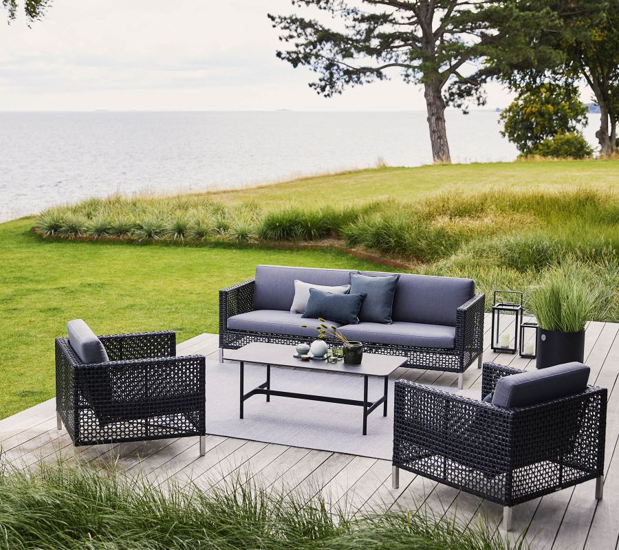 Connect 3-Sitzer Sofa in Grau von Cane-Line mit Sitzpolstern auf einer Terrasse.