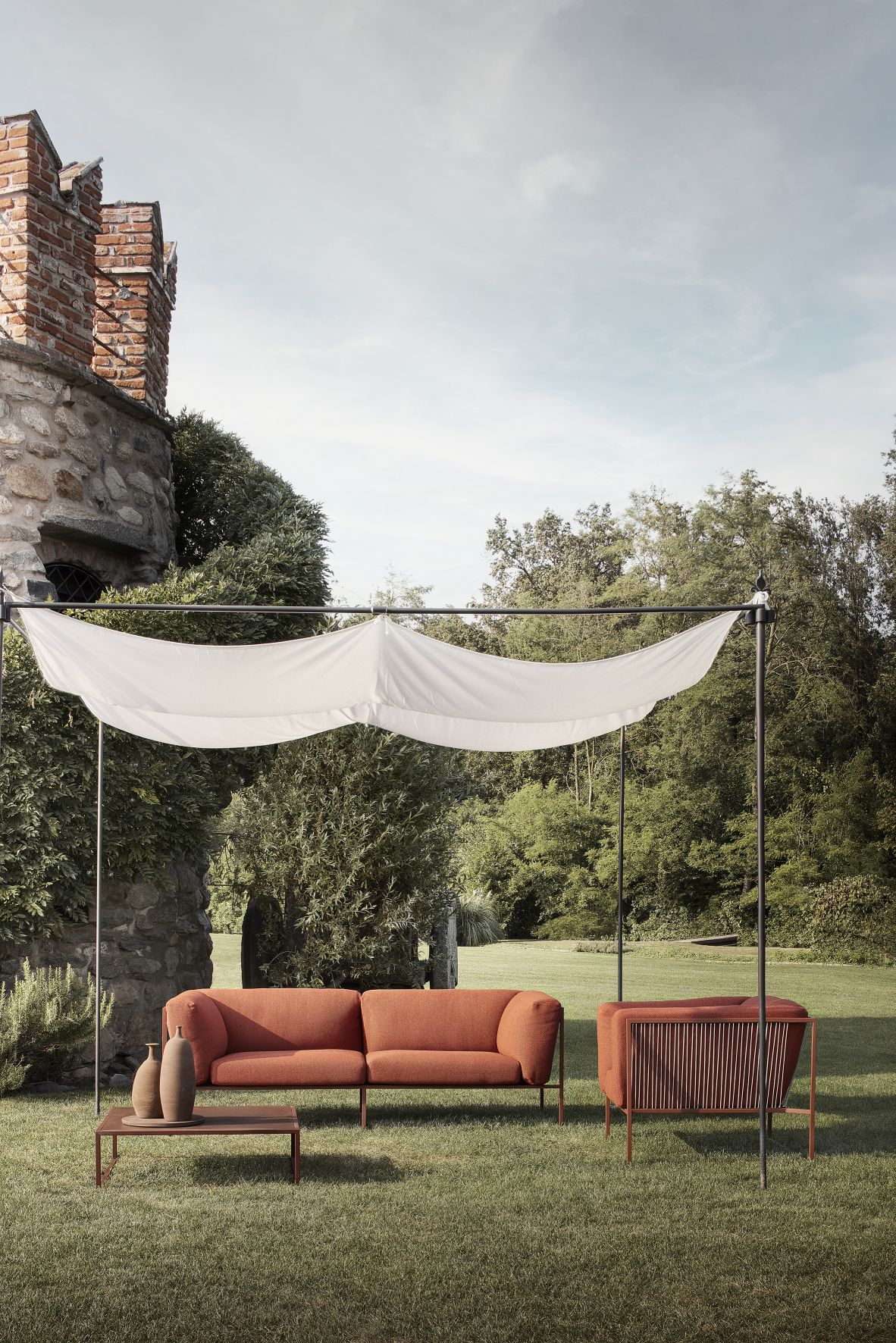 Arpa Outdoor Sessel von MDF Italia mit Sofa, Sessel und Tisch auf Rasenfläche.