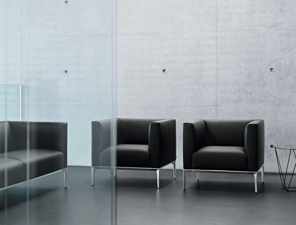 Schwarzer Jaan Sessel von Walter Knoll mit Metallbeinen vor einer Betonwand.
