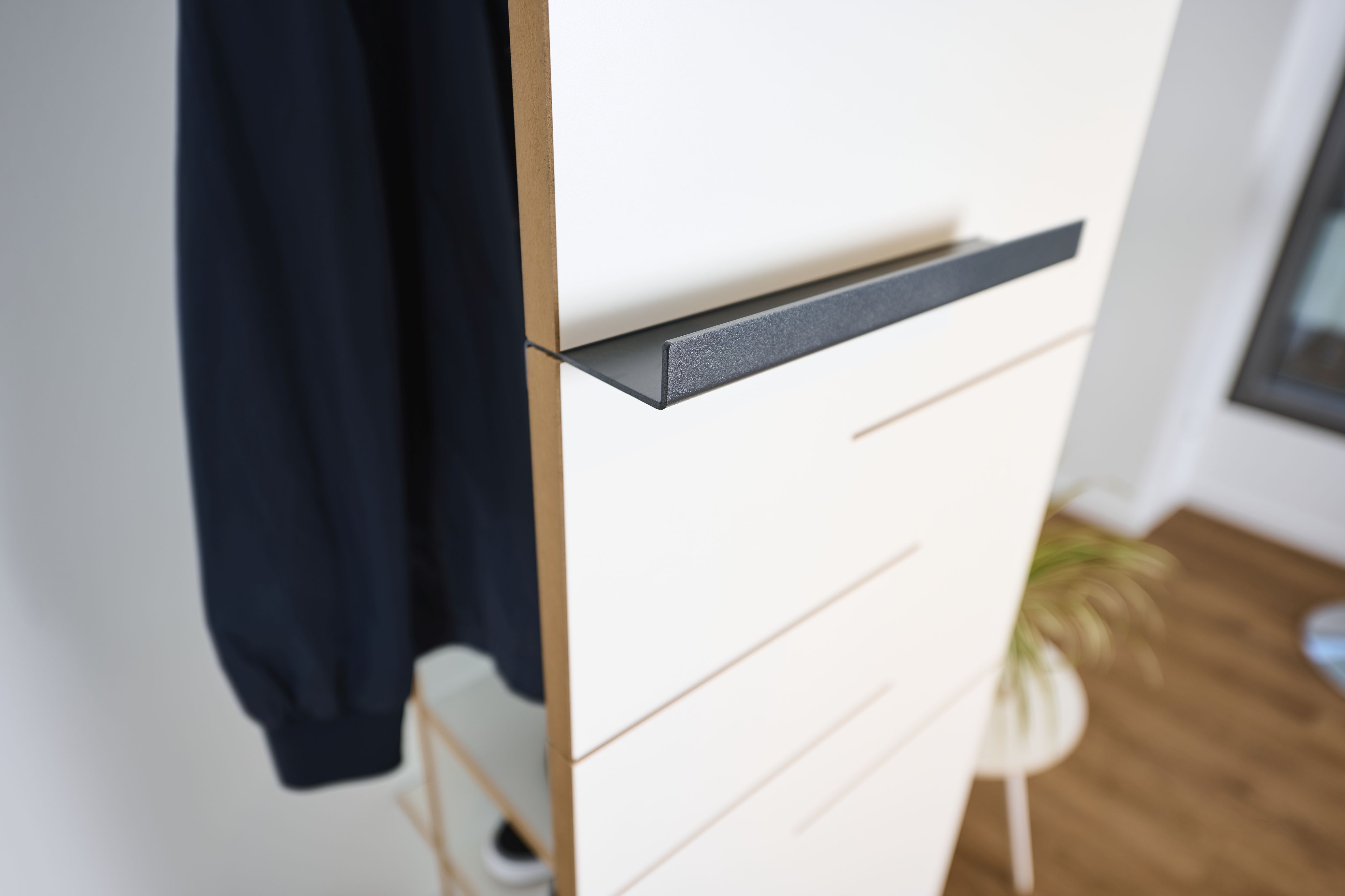 Detailaufnahme der Tojo Ablage: Modernes Wandregal mit schwarzer Ablage und hängender Jacke.