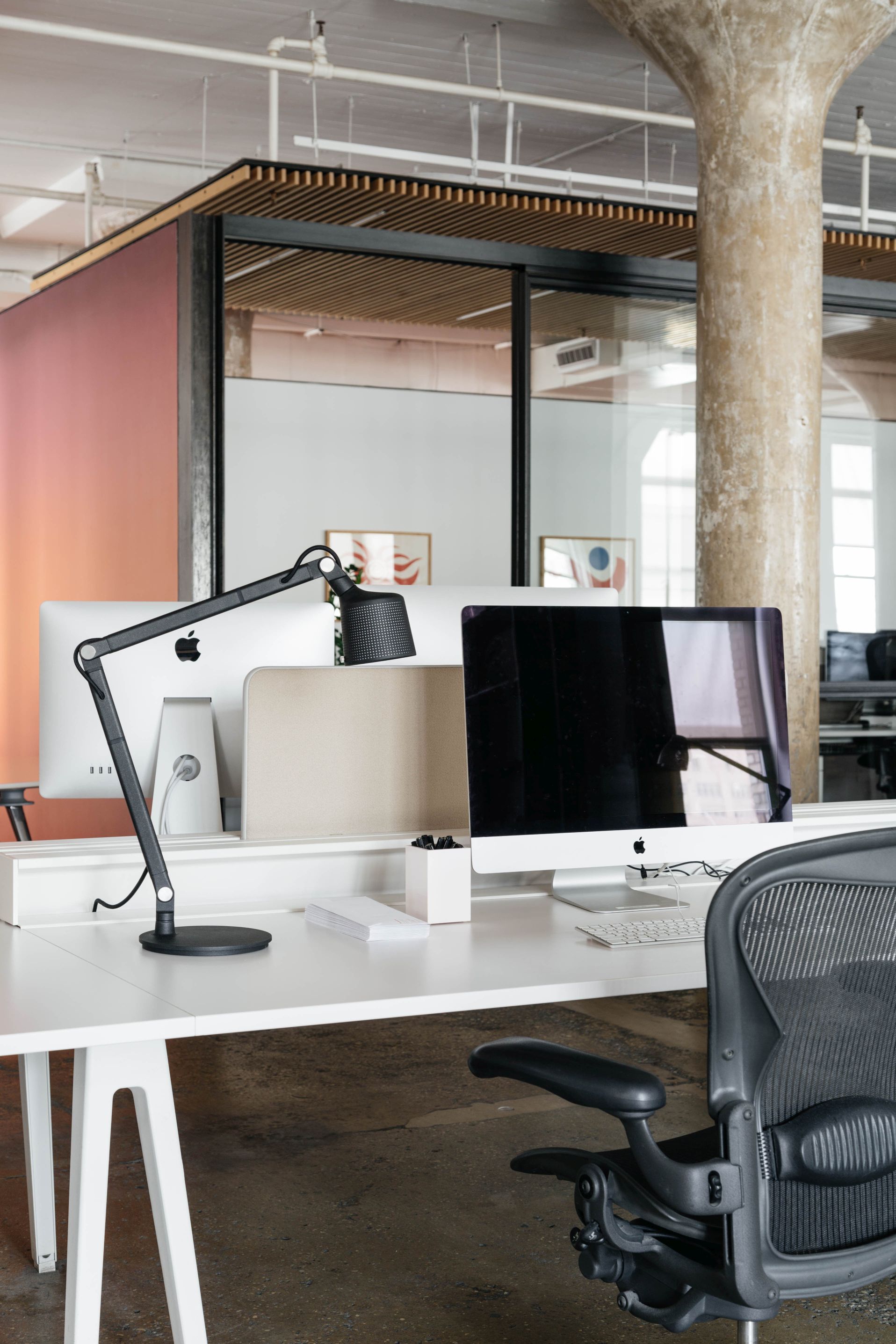 Schwarze Vipp Tischlampe auf weißem Schreibtisch im modernen Büro mit Computern und Büromaterial.