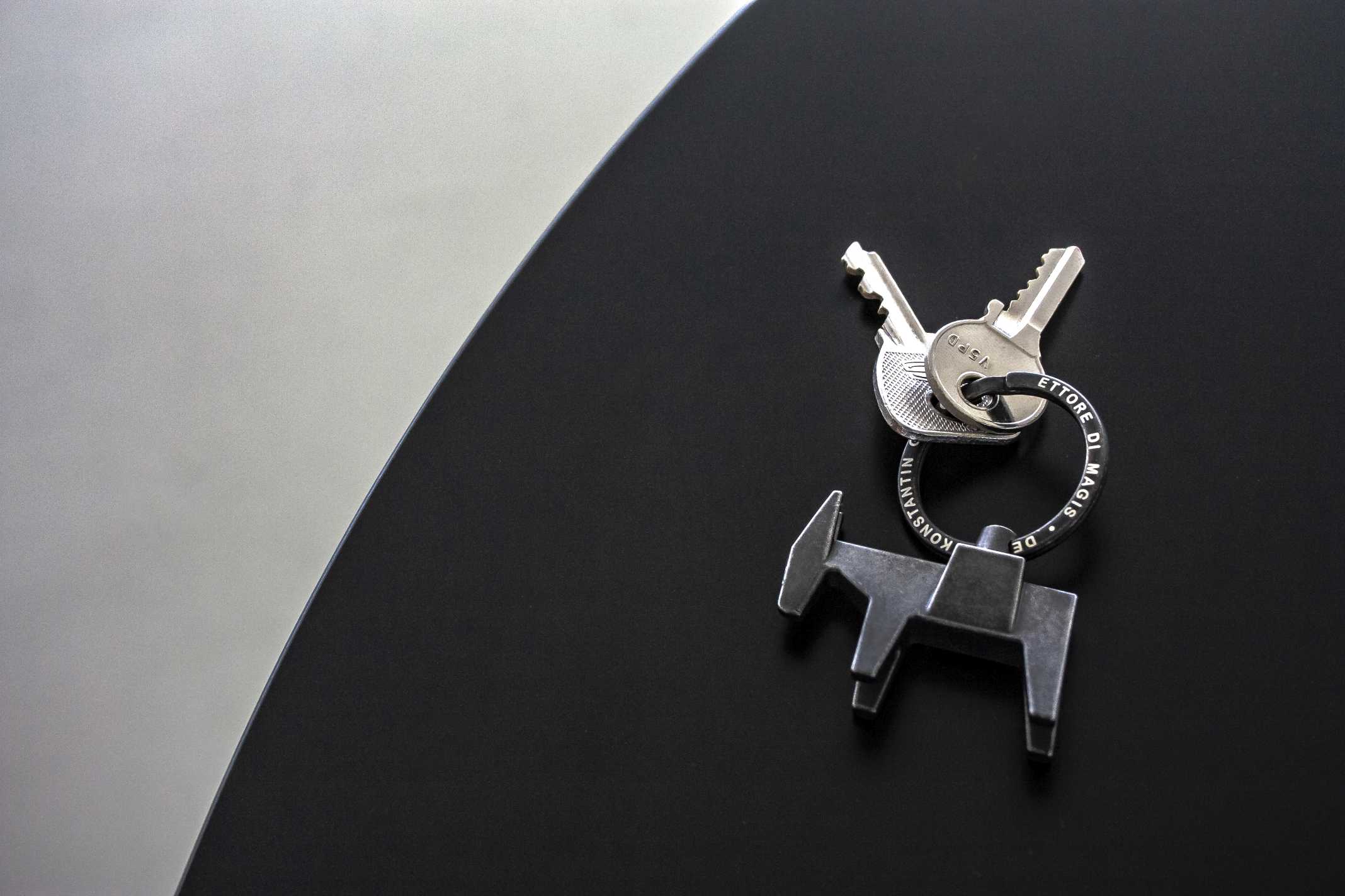 Ettore Schlüsselanhänger Magis mit Schlüssel und Esel-Anhänger aus Metall auf schwarzem Hintergrund.