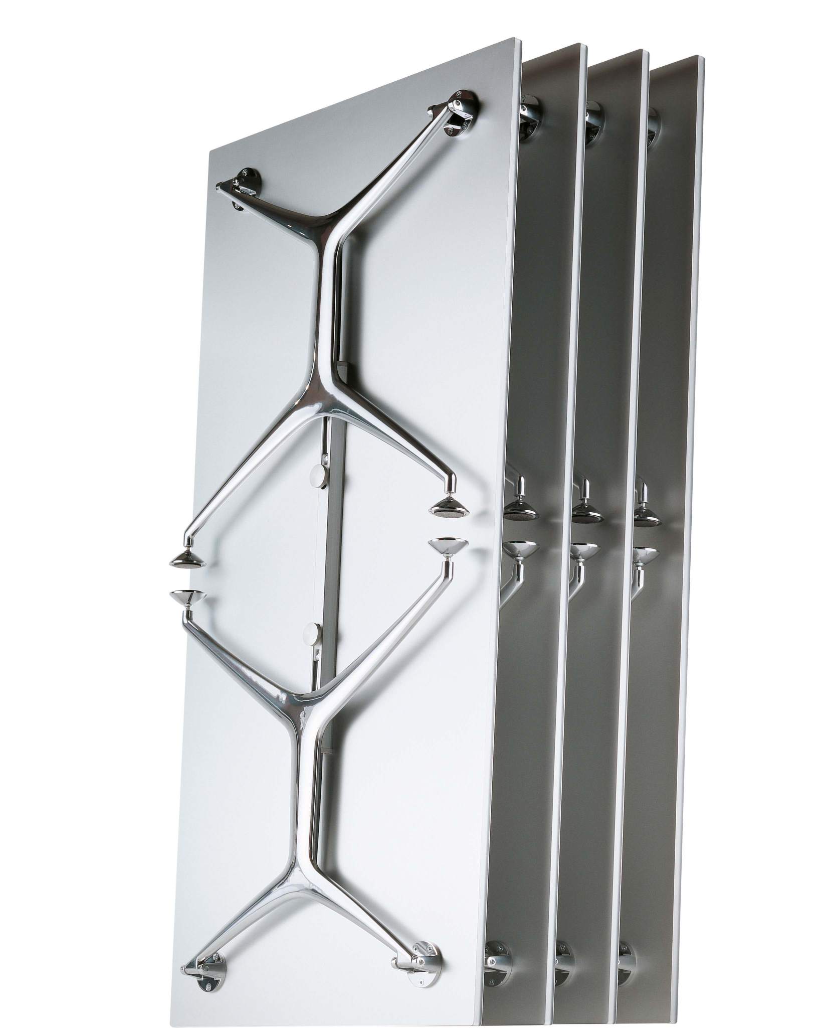 Frametable Tisch Alias: Vier zusammengeklappte, platzsparende Tische mit verchromten Tischbeinen an einer Wand.