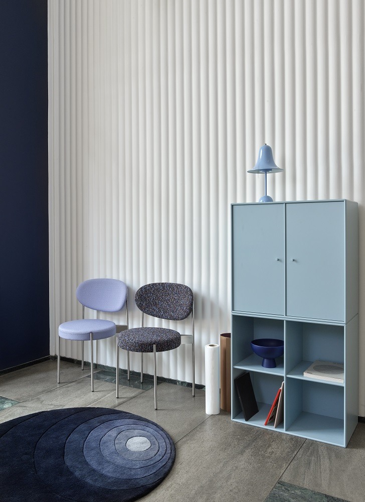 Pantop Tischleuchte in Hellblau auf einem blauen Schrank, stilvolles Interieur mit Stühlen und Teppich.