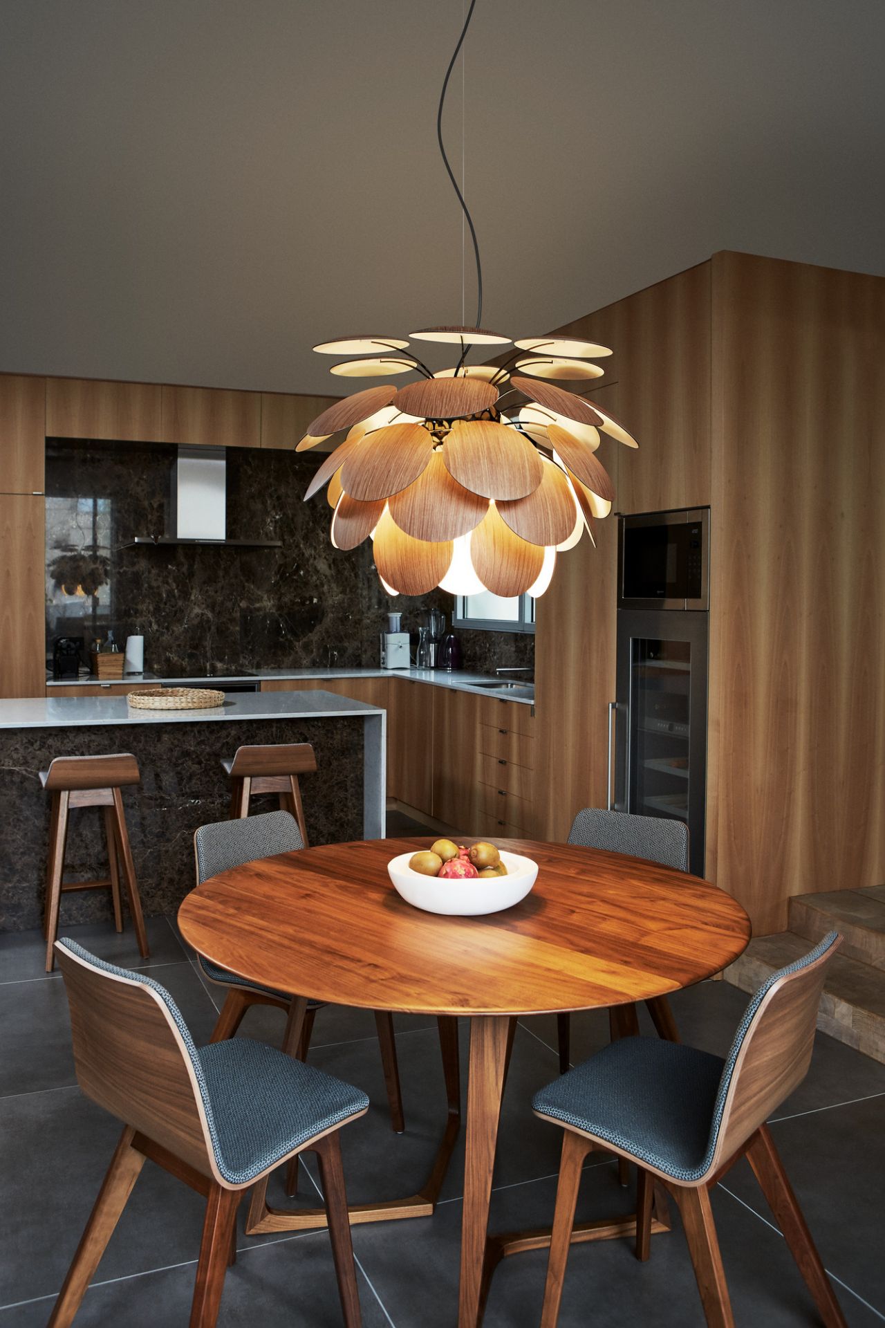 Moderne Holz-Pendelleuchte in Blütenform über einem Esstisch mit Stühlen in einer stilvollen Küche.