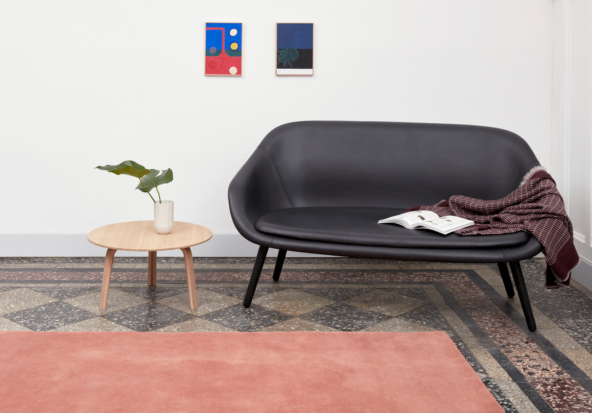 Schwarzes About a Lounge Sofa von Hay mit Decke und Tisch auf gemustertem Boden.