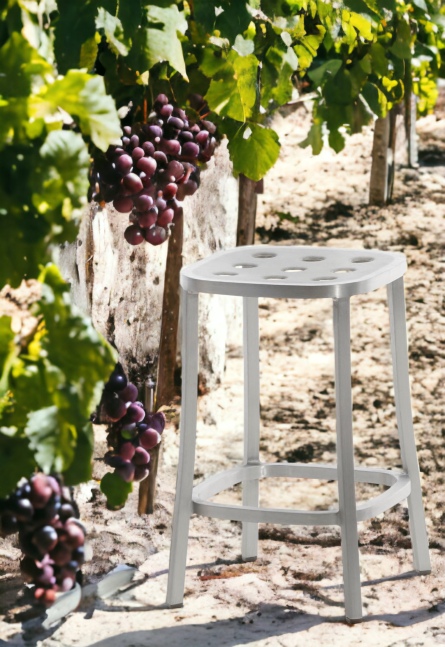 Emeco 1 Inch Aluminium Barhocker in Silber vor einem Weinberg mit reifen Trauben.