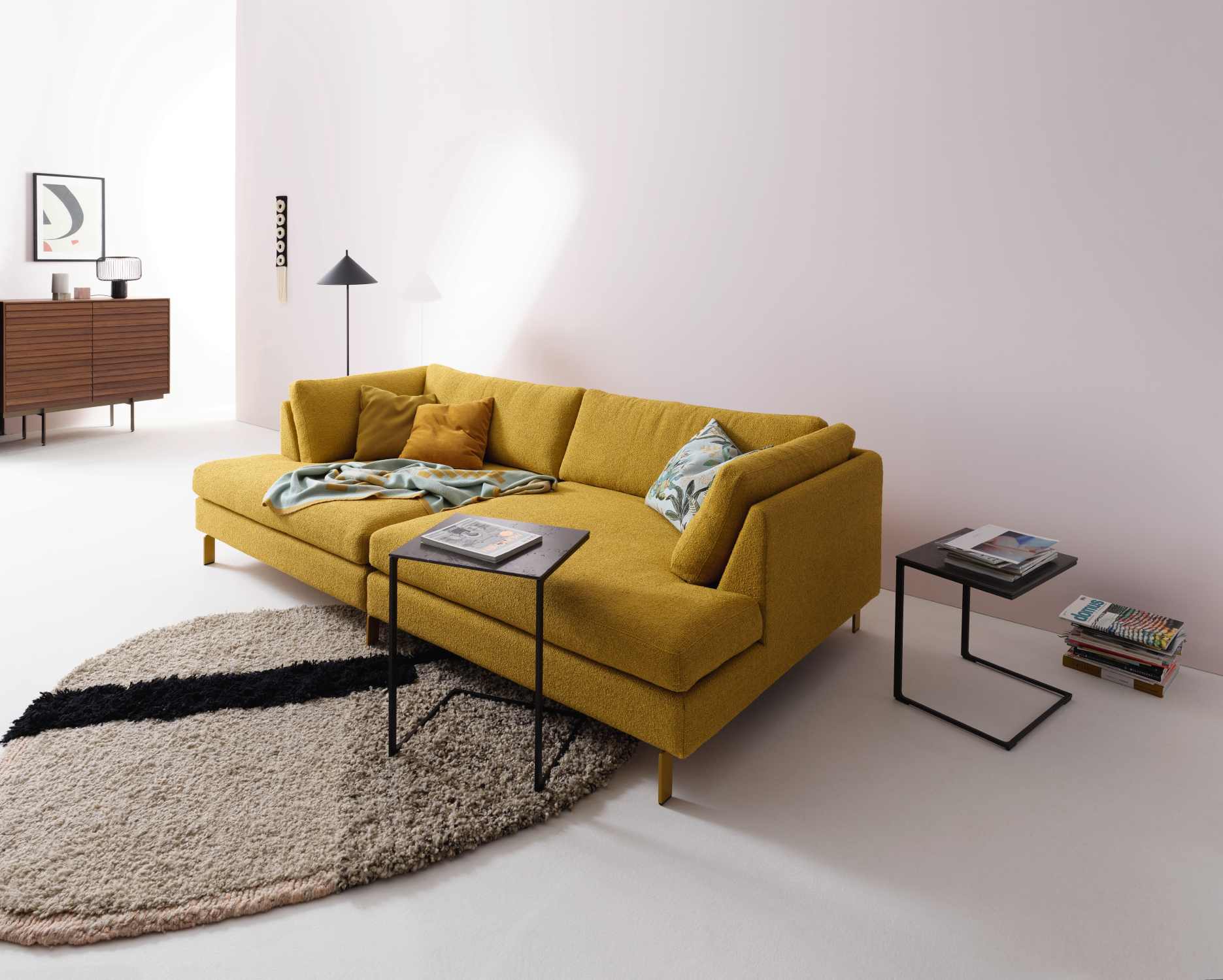 Gelbes Conseta Sofa von Cor mit Ottomane, Kissen und Beistelltischen auf modernem Teppich.
