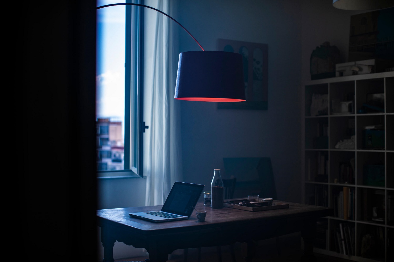 Twiggy Stehleuchte von Foscarini über einem Schreibtisch mit Laptop in einem dunklen Raum.