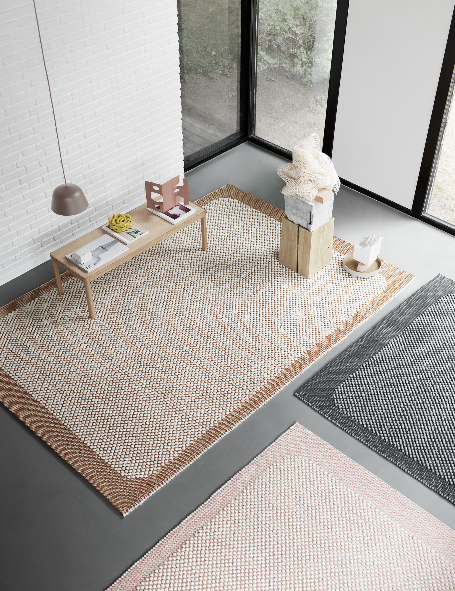 Draufsicht von drei Teppichen, darunter der Muuto Workshop Coffee Table Couchtisch, in einem hellen, modernen Raum.