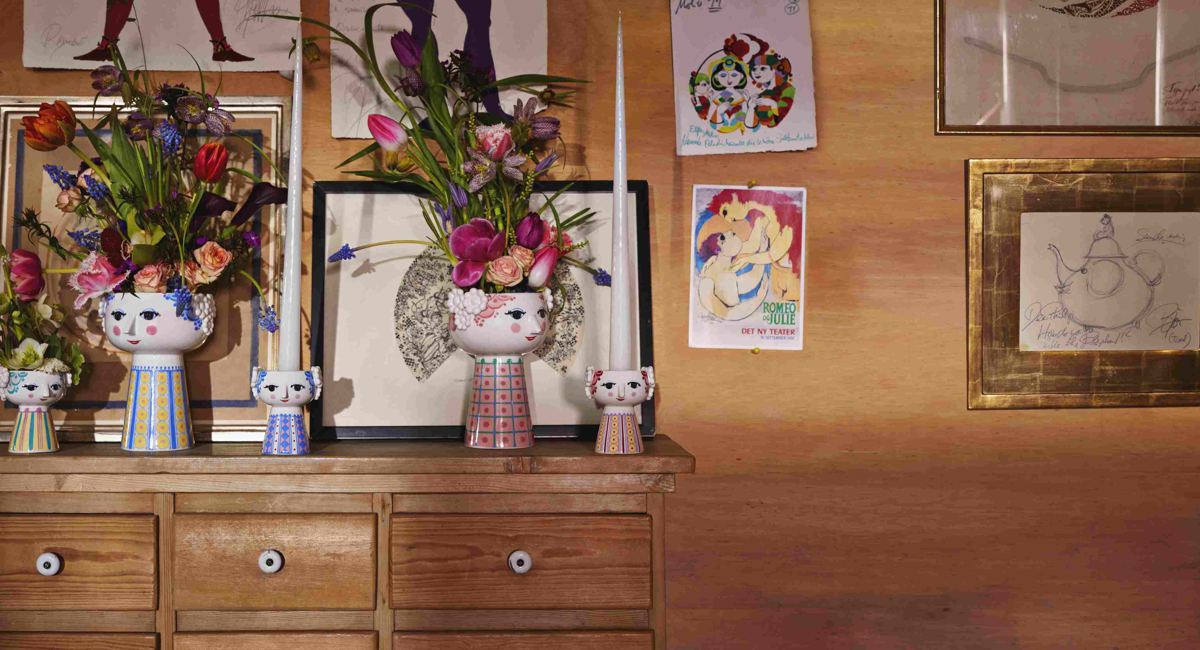 Keramik-Blumenvasen und Kerzenständer in Gesichtsform auf einer Holzkommode, dekoriert mit Blumen und Kerzen.