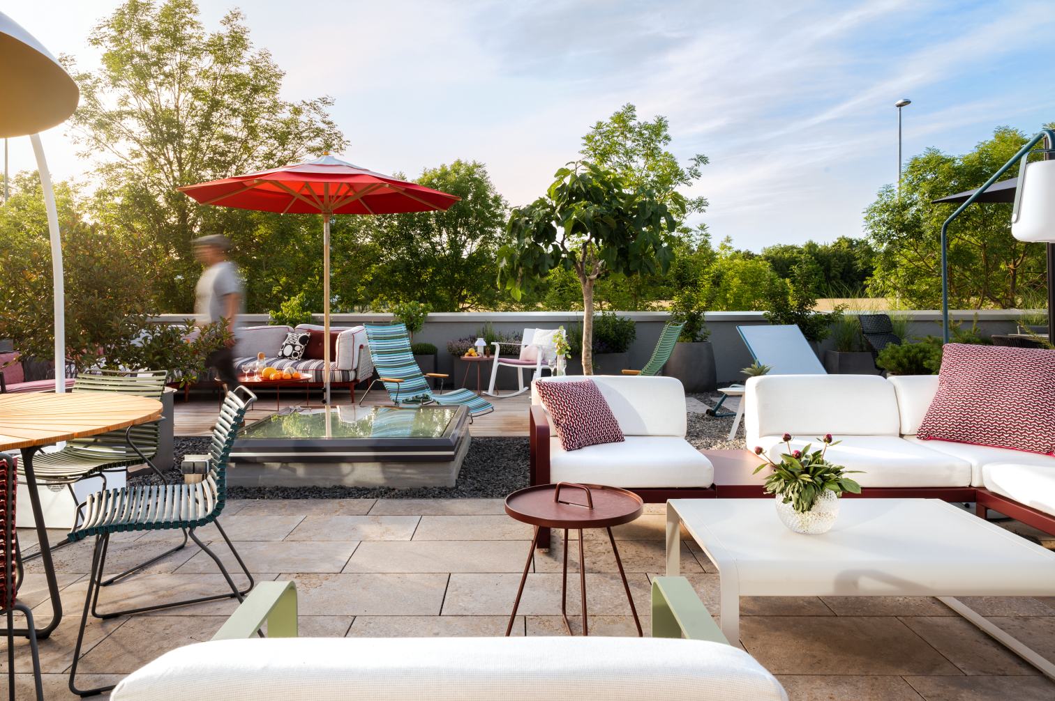 Dachterrasse mit modernen Gartenmöbeln: Lounge Sofa, Tisch, Stühle und Sonnenschirm für entspannte Stunden im Freien.
