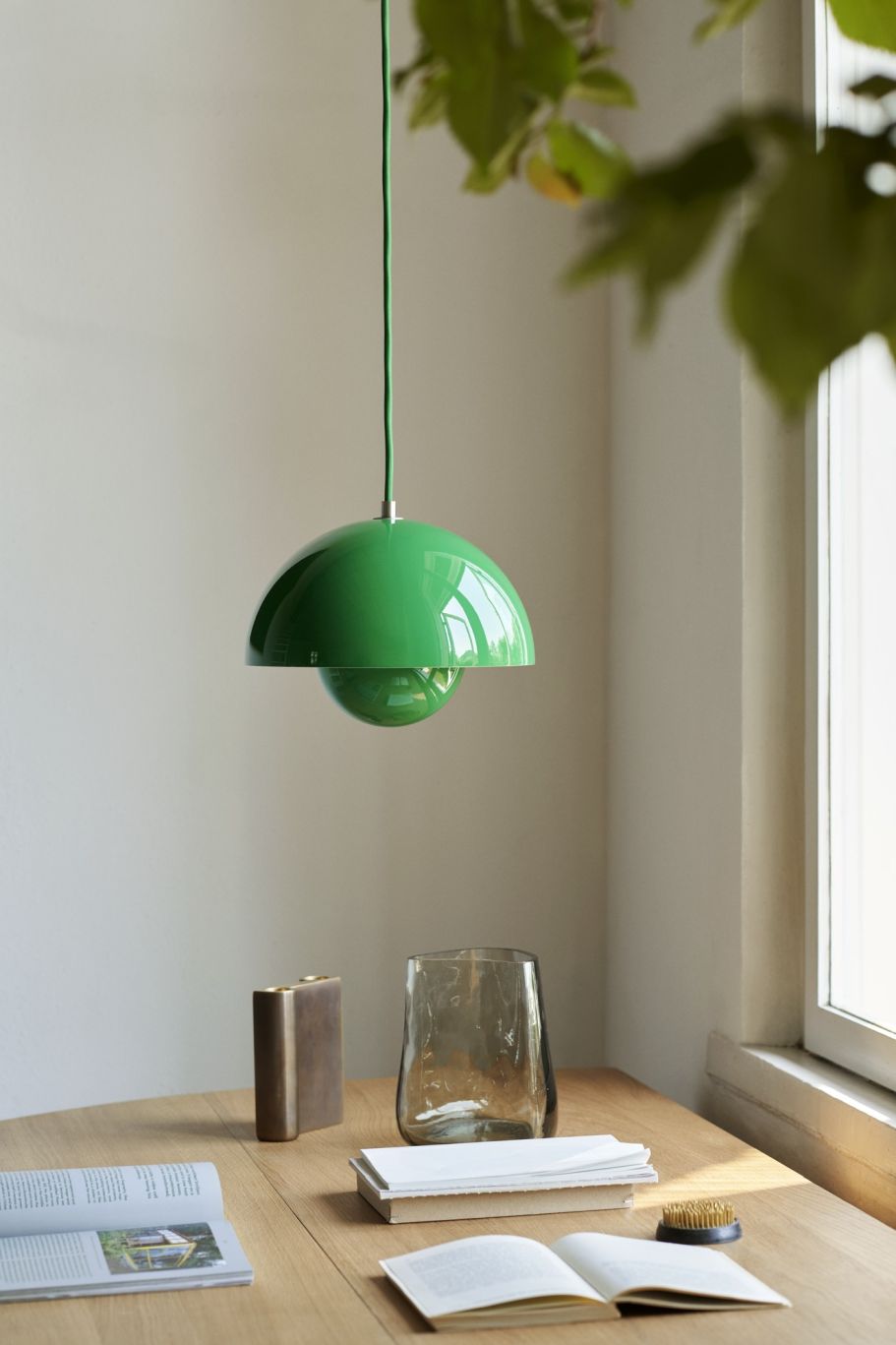 Grüne Flowerpot Pendelleuchte von AndTradition hängt über einem Tisch mit Buch und Dekoration.