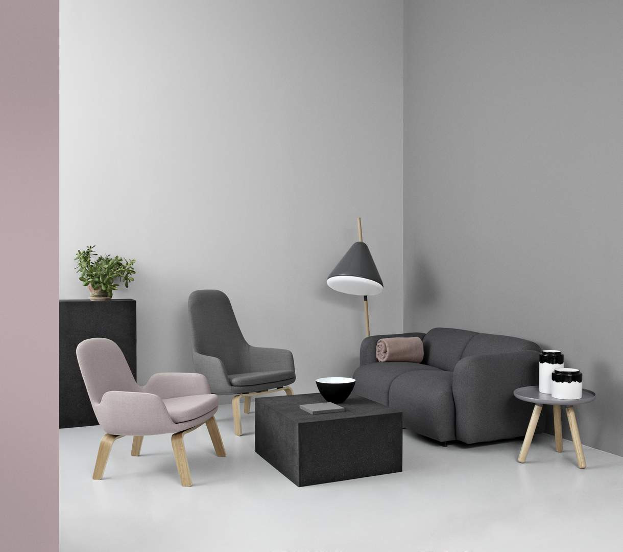 Modernes Wohnzimmer mit grauem Sofa, Sesseln in Rosa und Grau, Lampe und Couchtisch.