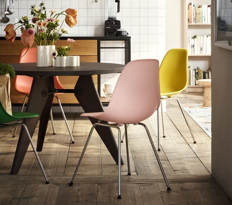 Esszimmer mit rundem Tisch und bunten Designstühlen aus Kunststoff mit Chrombeinen.