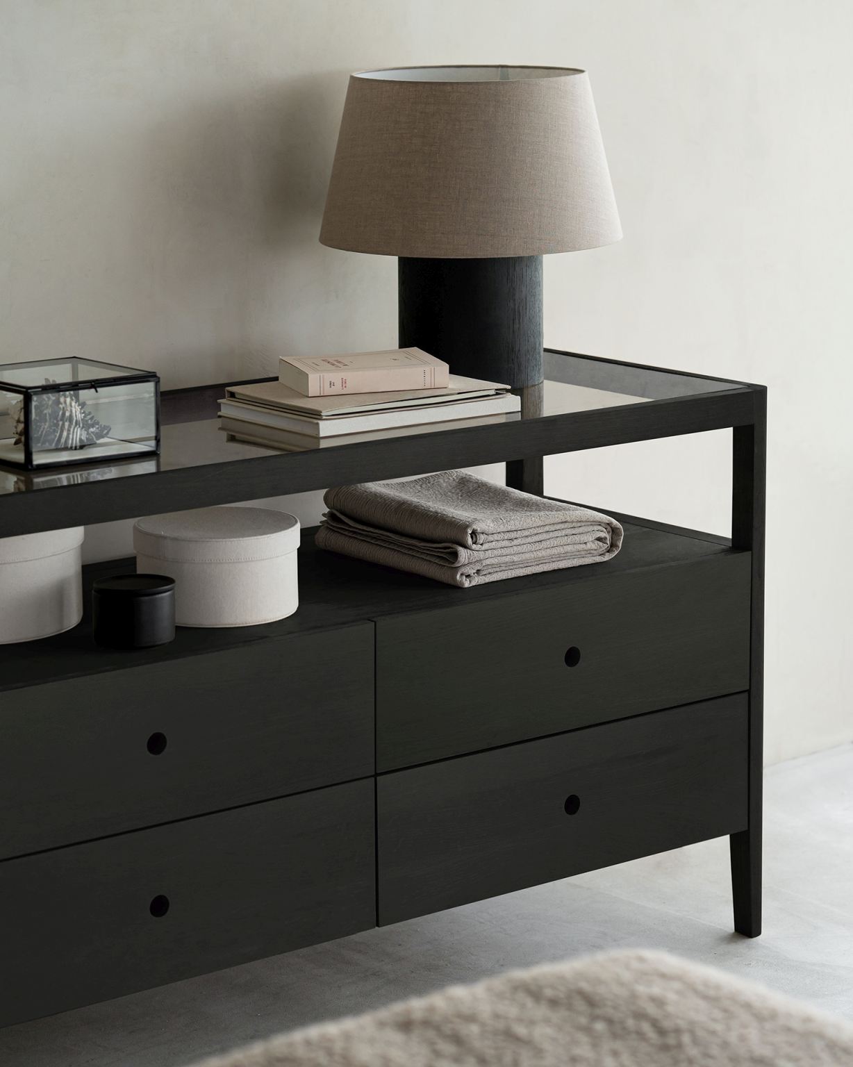 Spindle Kommode von Ethnicraft: Schwarze Holzkommode mit Schubladen und Deko-Elementen wie Lampe und Büchern.