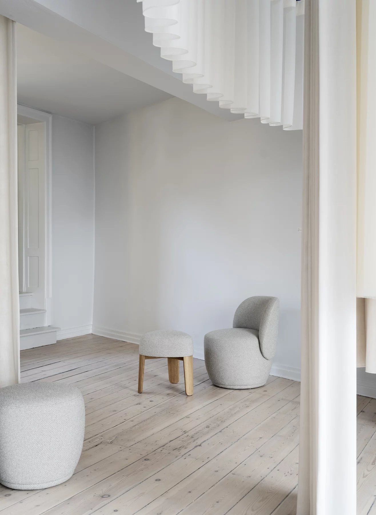 Kuon Sessel und Hocker in Taupe von Blomus Socia auf hellem Holzboden, minimalistisches Wohnzimmer.