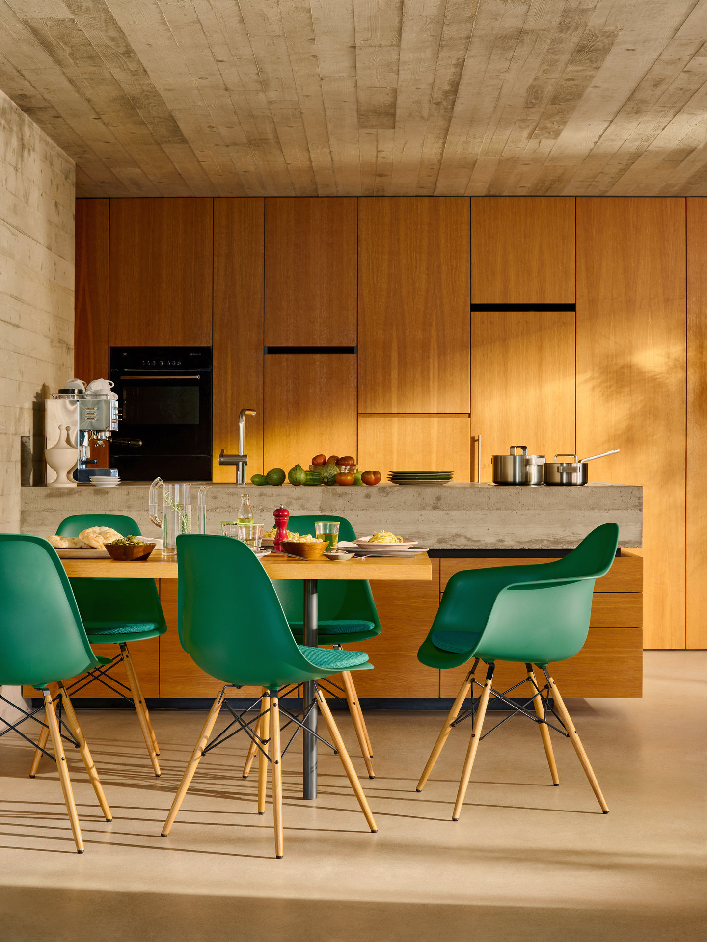 Grüne Eames Plastic Arm Chairs DAW Stühle mit Sitzpolster von Vitra am Esstisch in moderner Küche.