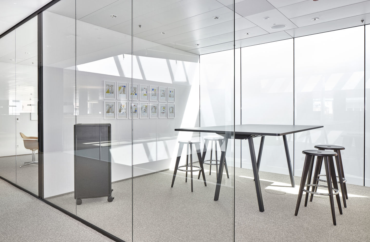 Moderner Konferenzraum mit schwarzem Tisch und Vitra Tabouret Haut Barhockern in Weiß und Dunkelbraun.